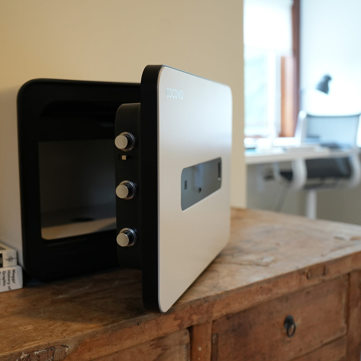 Cocono small home office safe in ivory in front of an office chair.